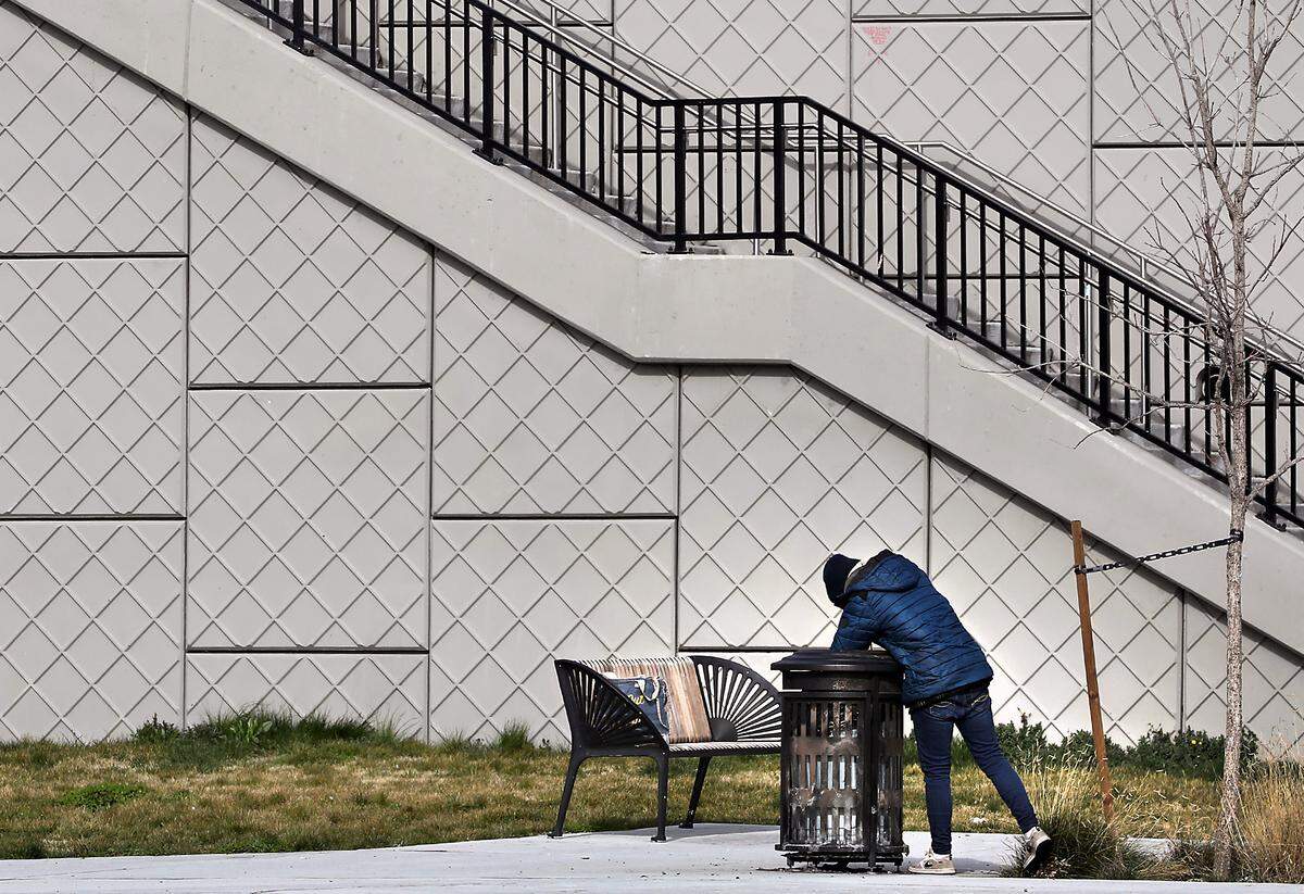 A homeless person searches in a trash can near the stairs for the Lewis Street Overpass near South Tacoma Street in Pasco. 